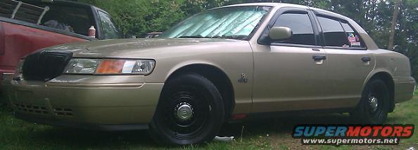 Gold 2000 Mercury Grand Marquis parked next to a red pickup truck