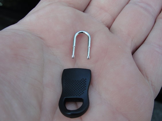 Zipper pull tab and metal U-shaped piece held in a hand