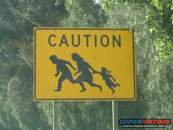Yellow caution sign depicting a family running