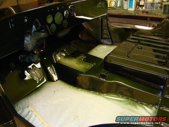 Interior of a dark green vehicle, likely a Jeep, during restoration. Dashboard and floor visible