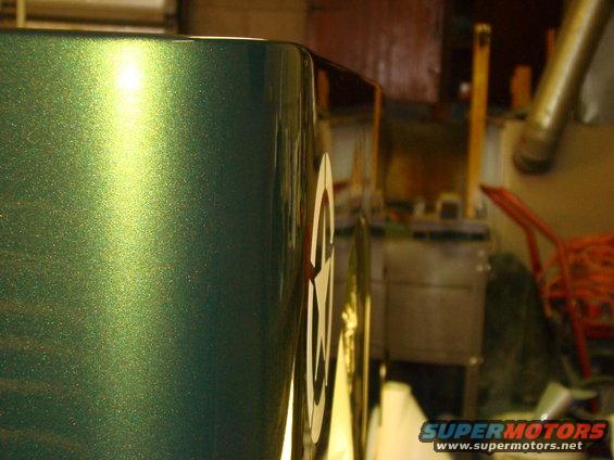 Close-up of a green metallic car body with white racing numbers '36' visible on the side