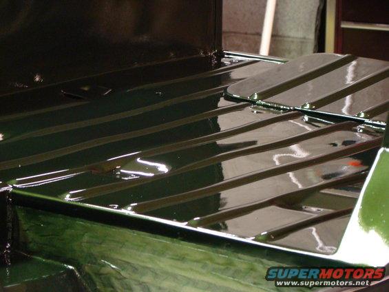 Green vehicle bed with ribbed flooring and a metal panel, reflecting light