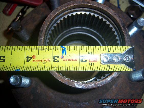 Measuring a vehicle hub with a yellow tape measure showing approximately 3.5 inches