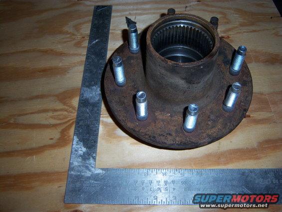 Wheel hub with six studs on a wooden surface, next to a metal ruler