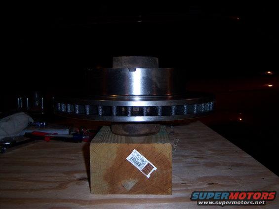 Brake rotor on wooden block, with tools in background