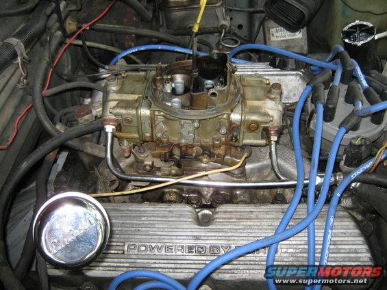 Engine bay showing carburetor, blue spark plug wires, and "POWERED BY" valve cover