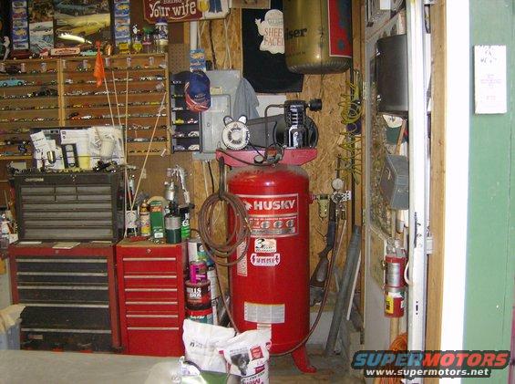 Garage interior with red Husky air compressor, tool chests, and shelves of model cars