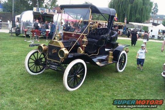 Black Ford Model T touring car with white-wall tires and brass accents. License plate reads "119855"