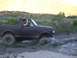 1987 Ford Bronco - Driver waves from a 1987 Ford Bronco as it navigates through a muddy off-road trail.