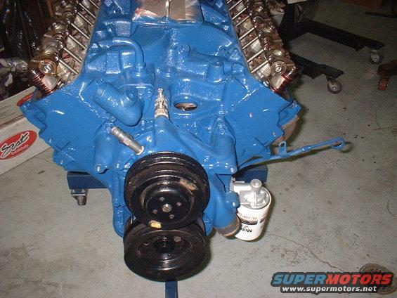 Blue engine block with dual pulleys and oil filter. Text on oil filter is partially visible