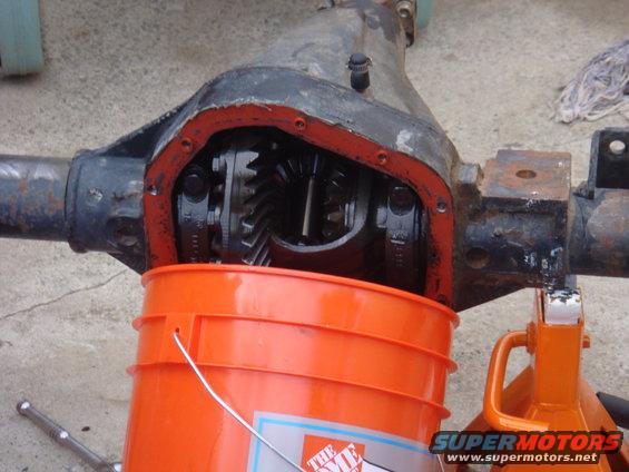 Differential housing with gears exposed, orange bucket underneath