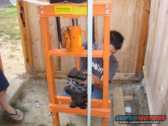 Guy using an orange press to work on a differential