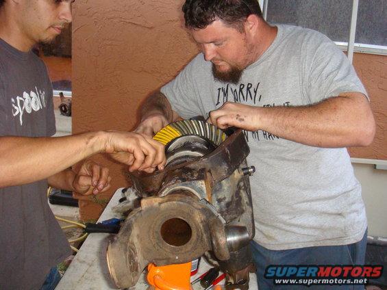 Differential assembly with yellow and black gears being worked on by two men