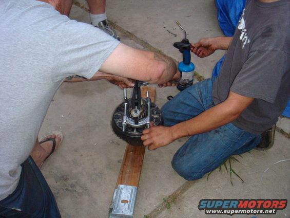 Mechanics working on a brake rotor and caliper assembly with a torch