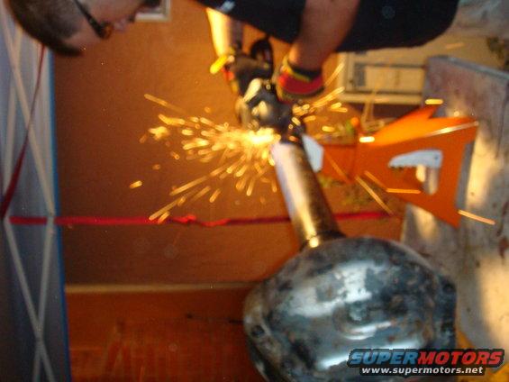 Axle part being cut with grinder, sparks flying