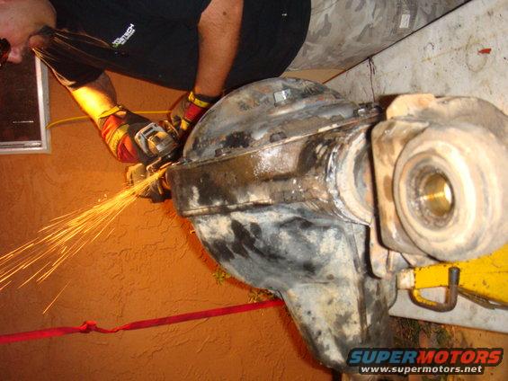 Person grinding on a rusty differential housing with sparks flying