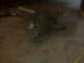 1994 Ford F-250 - A dark transmission part lies on a concrete floor, with some wires visible in the background.