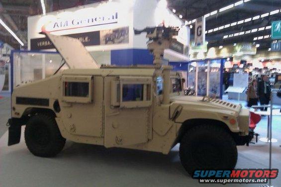 Tan Humvee with open hood and mounted weapon, viewed from the front-right
