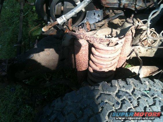 Close-up of rusty engine and suspension parts with a tire tread visible