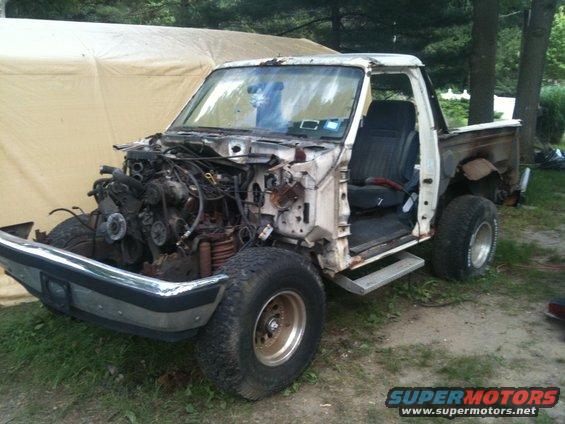 White Ford truck missing front clip and engine, showing interior and rear bed
