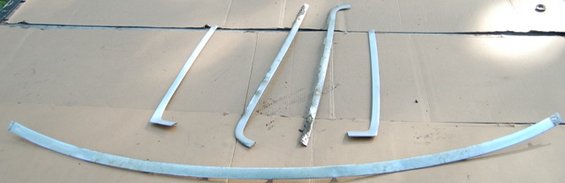 Several curved and straight metal trim pieces laid out on a cardboard surface