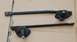1988 Ford Bronco - Pair of windshield wiper arms and their bases, photographed on a flat surface.