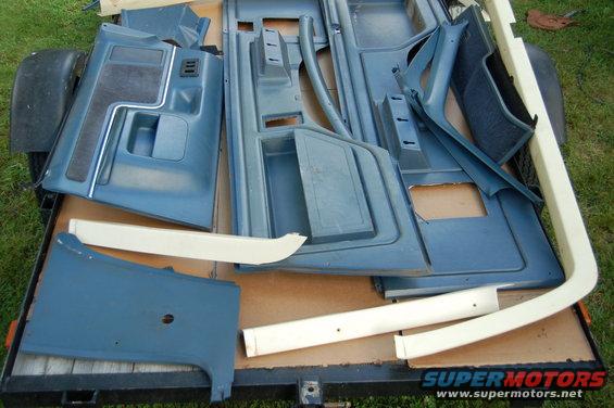 Blue interior door panels and trim pieces laid out on a trailer
