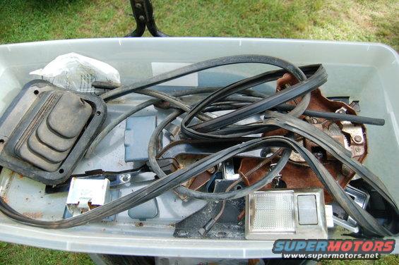 Bin of assorted vehicle parts including a shifter boot and weather stripping
