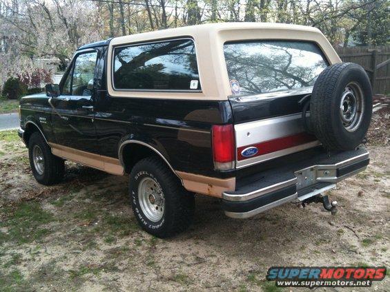 Black Ford Bronco with tan trim and a tan removable top. Spare tire mounted on the back