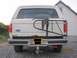 1989 Ford Bronco - Rear view of a white 1989 Ford Bronco, showing its spare tire carrier and some rust on the tailgate.