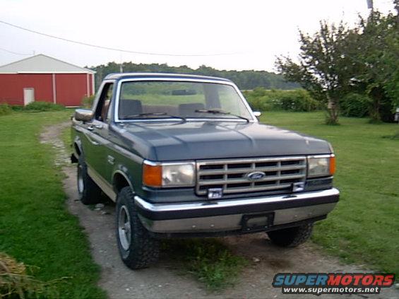 Dark blue pickup truck, 3/4 front view. Grille indicates 1987