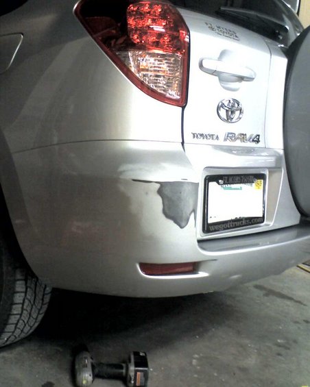 Silver Toyota RAV4 rear bumper with scraped paint and a license plate that reads 'wegottrucks.com'