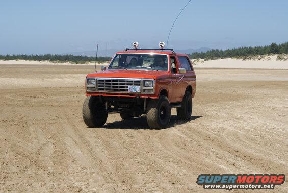 Orange Ford Bronco with lifted suspension and large tires on a sandy beach, license plate 419 EPJ