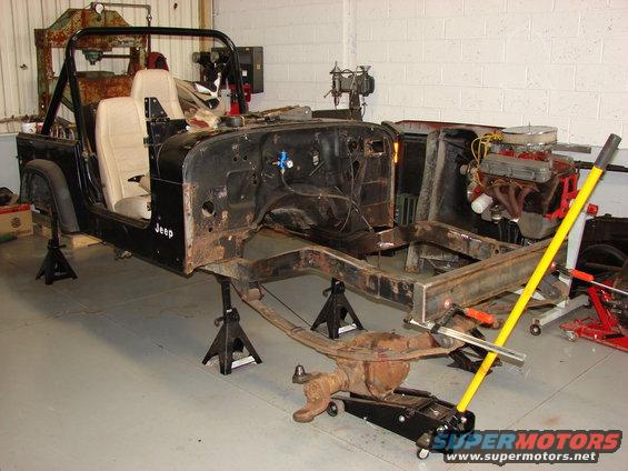 Jeep body on jack stands with engine exposed, front axle removed