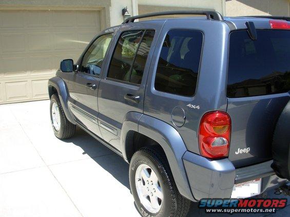 Gray 2002 Jeep Liberty parked in front of a garage, showing the rear passenger side