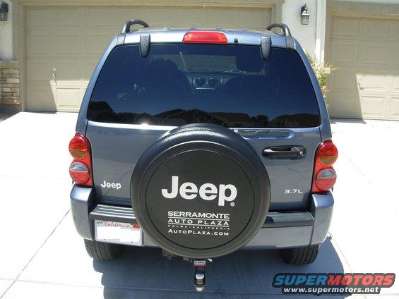 Rear view of a gray Jeep Liberty with a spare tire cover. It has a 'Jeep' logo and '3.7L' badge