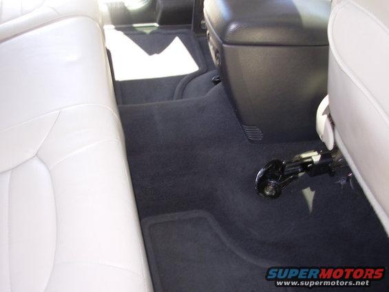 Interior view of a vehicle showing light-colored seats, dark carpet, and a center console