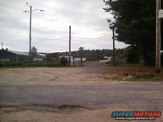 White pickup truck parked near a gate, distant view