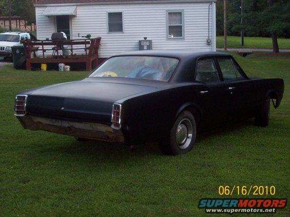 1966 Oldsmobile Cutlass sedan, matte black, rear view, missing rear bumper assembly