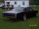 1966 Oldsmobile Cutlass - Matte black 1966 Oldsmobile Cutlass sedan parked on grass, undergoing restoration.
