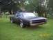 1966 Oldsmobile Cutlass - A matte black sedan sits in a grassy yard with trees and a house in the background. The rear bumper is removed.