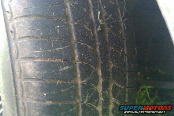 Close-up of a worn tire with grass and debris in the tread
