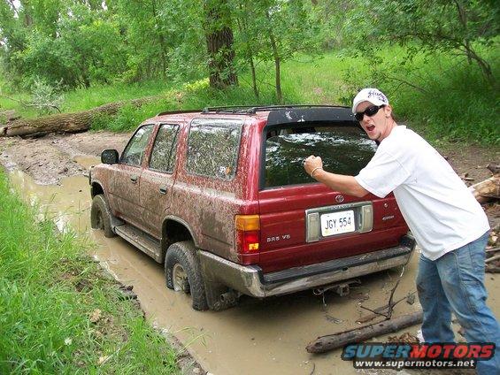 Red Toyota 4Runner stuck in mud, man posing behind it. License plate JGY 554