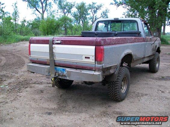 Rear view of a red and silver pickup truck with a strap on the tailgate and a license plate reading JDG 566