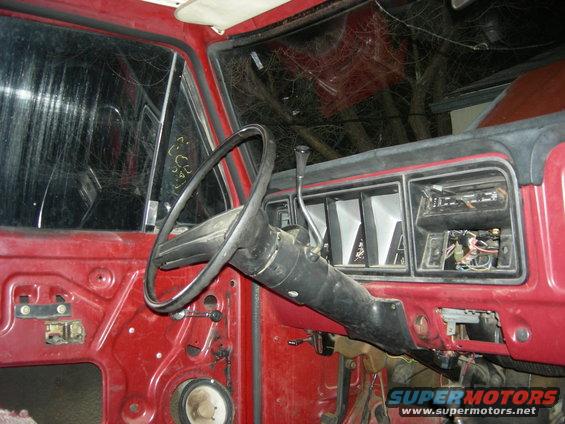 Interior of a red vehicle, showing dashboard, steering wheel, and door panel removed