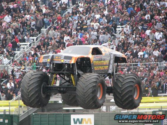 Monster truck with "Maximum Destruction" text, orange and grey body, in mid-air