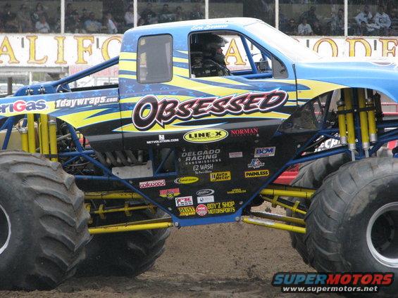 Monster truck with 'Obsessed' graphic, yellow suspension, and large tires