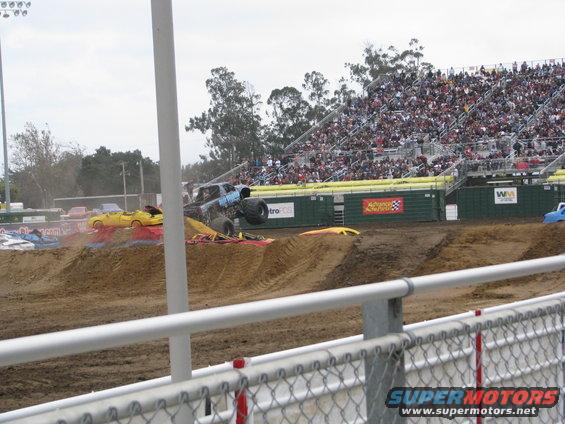 Monster truck jumping over yellow car at event