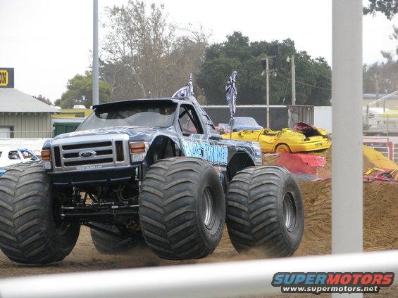 Monster truck with huge tires, front view. Yellow car crushed in background
