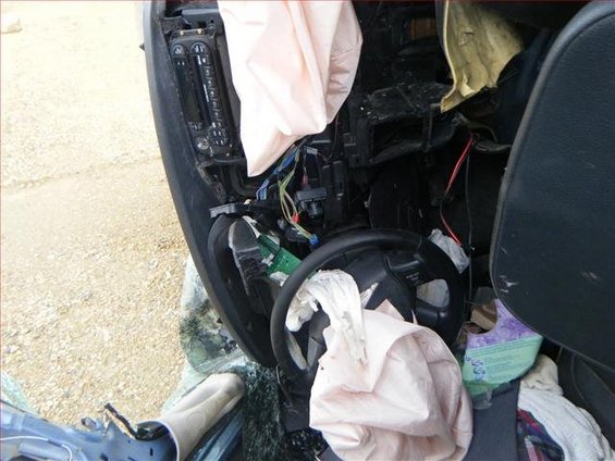 Damaged car interior showing deployed airbags, steering wheel, and dashboard components